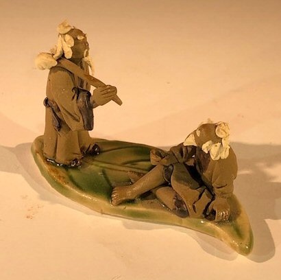 Miniature Ceramic Figurine Two Mud Men On A Leaf, One Standing Holding A Bag, The Other Sitting - 2"